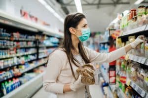 Personne faisant les courses en magasin, sélectionnant des produits alimentaires pour une livraison à domicile.