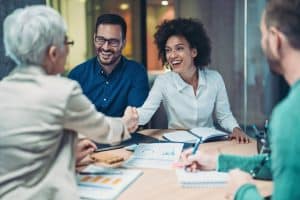 Personnes travaillant ensemble autour d’une table, échangeant des documents lors d’une assistance administrative à domicile.
