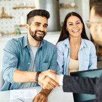 Personnes en rendez-vous informatique à domicile, échangeant avec un technicien autour d’un ordinateur portable.