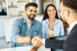 Personnes en rendez-vous informatique à domicile, échangeant avec un technicien autour d’un ordinateur portable.